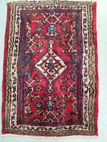 Top view of red hand knotted Persian Hamedan wool rug with tribal design patterns and white fringe edges.