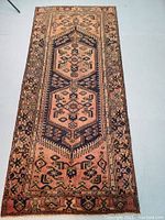 Full view of runner rug laid flat on floor showing double medallion and border motifs