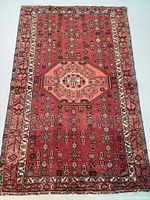 Top-down view of entire rug showing red field, central octagonal medallion and ivory border