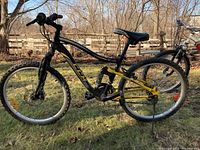 Side view showing the CCM mountain bike with black and yellow frame and knobby tires