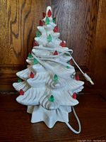 Front view showing ceramic Christmas tree with red and green lights, power cord wrapped around.