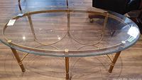 Full top view of oval glass top coffee table with brass finish frame showing the structure and surface condition.