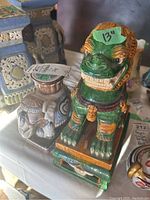 Ceramic green foo dog statue 13 inches tall alongside decorative elephant with a raised platform on its back, displayed on a table