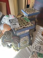 Front and side view of one ceramic elephant stand showing lattice top and detailed painted ceramic body with blue and brown tones.