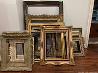 Seven assorted frames stacked against wall showing overall lot contents