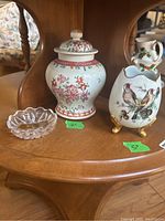 Three items displayed on wooden shelf: crystal dish left, floral ginger jar center, Limoges egg vase right