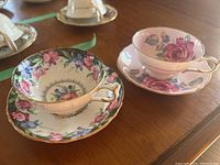 Both tea cup and saucer sets displayed on wooden surface