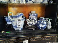Photo showing entire shelf with blue and white china pieces including pitcher, jar without lid, gravy boat, jars, oil and vinegar bottles, and bowls