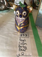 Front view of Royal Crown Derby bear figurine showing hand-painted blue and gold details and facial features.