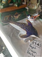 Porpoise figurine showing detailed gold decoration on blue paint, alongside waves at base.