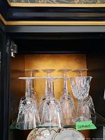 Seven waterford crystal wine glasses in two different sizes displayed inside a cabinet, showing intricate cut designs and crystal clarity.