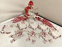 Wide view showing six ice skating snowman ornaments, two smaller snowmen, large snowman, and candy canes behind.