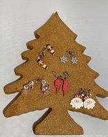 Five pairs of holiday earrings displayed on a cork tree stand showing various angles and details.