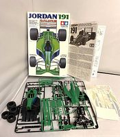 Front view of the Jordan 191 model kit box showing the car illustration, instruction sheet and decals, plastic sprues, four rubber tires and partially assembled car chassis and cockpit parts.