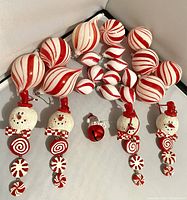 Overview of all ornaments: large and small peppermint swirl glass ornaments, six hanging snowmen, one red bell.