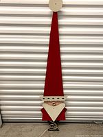 Front view of plywood Santa decoration with painted front, tall red hat, white beard, and red coat, showing condition and design details.