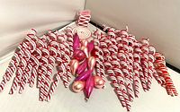 Candy cane shaped plastic ribbon candy ornaments with red and white stripes alongside a spiral lollipop shaped ornament.