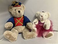 Photo of two plush bears, one dressed as a tin soldier and the other as a sugarplum fairy, placed side by side against a plain background.