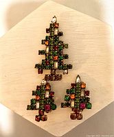 Front view of vintage rhinestone Christmas tree pin and matching clip earrings showing multicolored stones and overall design.