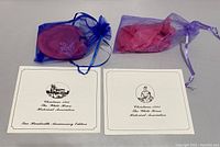 Two white cover brochures from 1980 and 1981 White House Historical Association Christmas ornaments, with blue and purple organza bags containing ornaments.