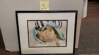 Framed mixed media artwork showing multiple overlapping faces with rich detail and color.