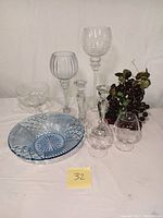 Full lot including blue crystal bowl, crystal glasses, candle holders and glass grapes displayed on white surface.