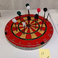 Dart board is laid flat showing darts inserted in different segments with visible numbering around the edge and colored sections