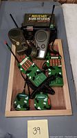 Overview of the military toy walkie talkies set including base station and handheld units in a wooden tray labeled 39.