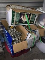 Stack of four boxes containing Nouvelle Noel Animated Illuminated 3 Dimensional Silhouettes, some unpacked and visible metal frame silhouettes with string lights inside, all stacked on and beside a red plastic storage tote. Boxes partially open, showing light sets.