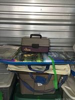 Photo of tote contents showing the Flambeau tackle box and Plano storage box on top of a colorful boogie board.