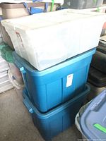 Three large storage totes stacked, containing kitchen items.
