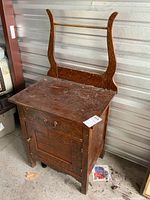 Front view of the wood washstand showing the rectangular top surface with wear, cabinet door below, and curved side supports.