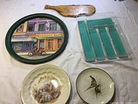 Photo of the wooden charcuterie board, serving tray, two decorative plates, the silverware organizer rack, and a wooden paddle-shaped item on a white background.
