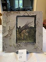 Front cover of Led Zeppelin IV vinyl showing peeling dust jacket and framed painting of man carrying sticks.
