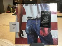Front cover view of Bruce Springsteen "Born in the USA" LP in original shrink wrap with slight tear.
