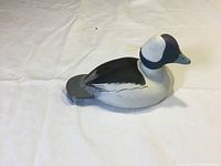 Side view of mini carved and painted wooden bufflehead drake decoy, showing full body profile and paint detail.