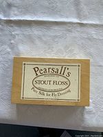 Photo of Pearsall's Stout Floss wooden box with label on top, stating 'Pure Silk for Fly Dressing'.