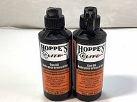 Front view of two black bottles of Hoppe's Elite Gun Oil, showing the product name, volume, and key features on the label