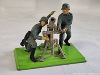 Front angle of WWII German mortar and two soldier figures on green base, showing detail and condition.