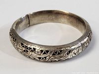 Full view of the silver bracelet showing the dragon embossing and cutouts.