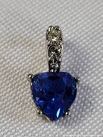 Close-up front view of the heart-shaped blue sapphire pendant showing the stone's color and the accented bail.