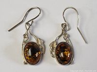 Front view of the pair of sterling silver earrings with amber stones and leaf-like silver details.