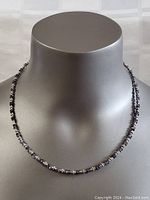 Full view of the necklace on a grey display bust, showing the entire length and overall design.