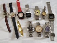 Overview photo of 11 vintage watches laid flat showing variety in band materials and watch face designs.