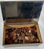 Photo of the open metal box filled with vintage copper pennies showing the cedar-lined interior and art deco patterned lid.