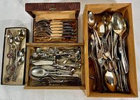Set of boxes with various silver plated flatware items including knives, large spoons, forks and serving spoons all arranged as found in the estate.