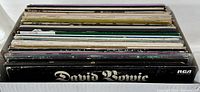 Box filled with multiple vintage 12 inch LP records viewed from top showing record spines and edges.