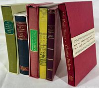 Full view of 6 hardcover Folio Society books standing with original slip-covers, showing book titles and colors.