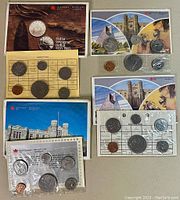 Overview of several vintage Canada proof like coin sets in sealed Canadian Mint packaging laid flat with visible coins and packaging detail.