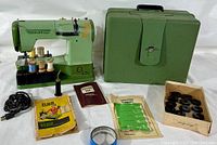 Full lot including the green ELNA Supermatic sewing machine, carrying case, sewing thread spools, oil can, manuals, and accessories.